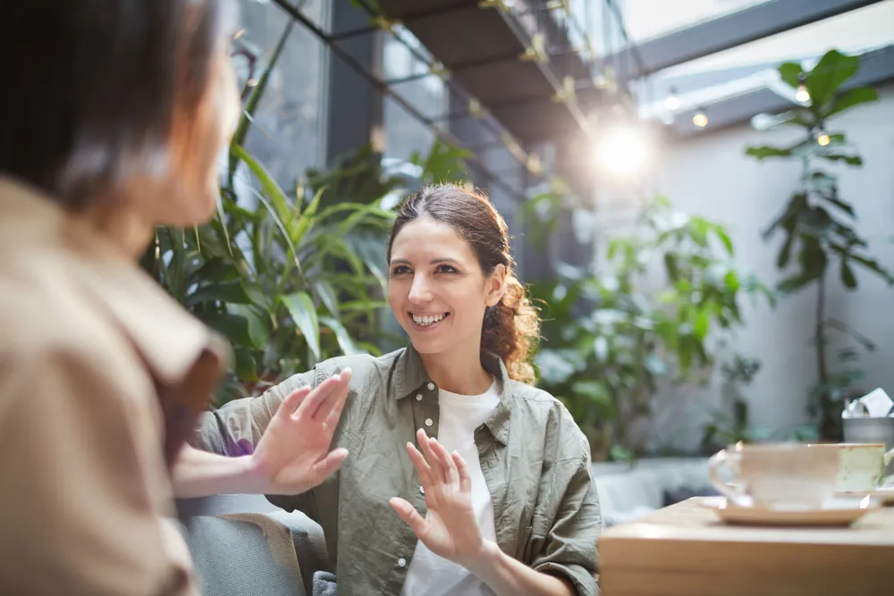 Two people having a confident, natural conversation at a cafe - no accent barrier